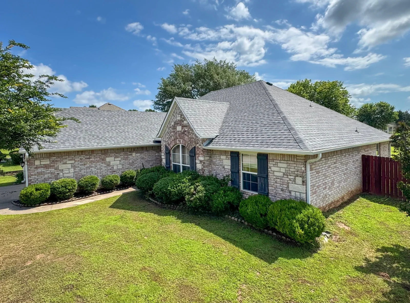Gray architectural shingle roof on brick home with multiple peaks and arched entry detail